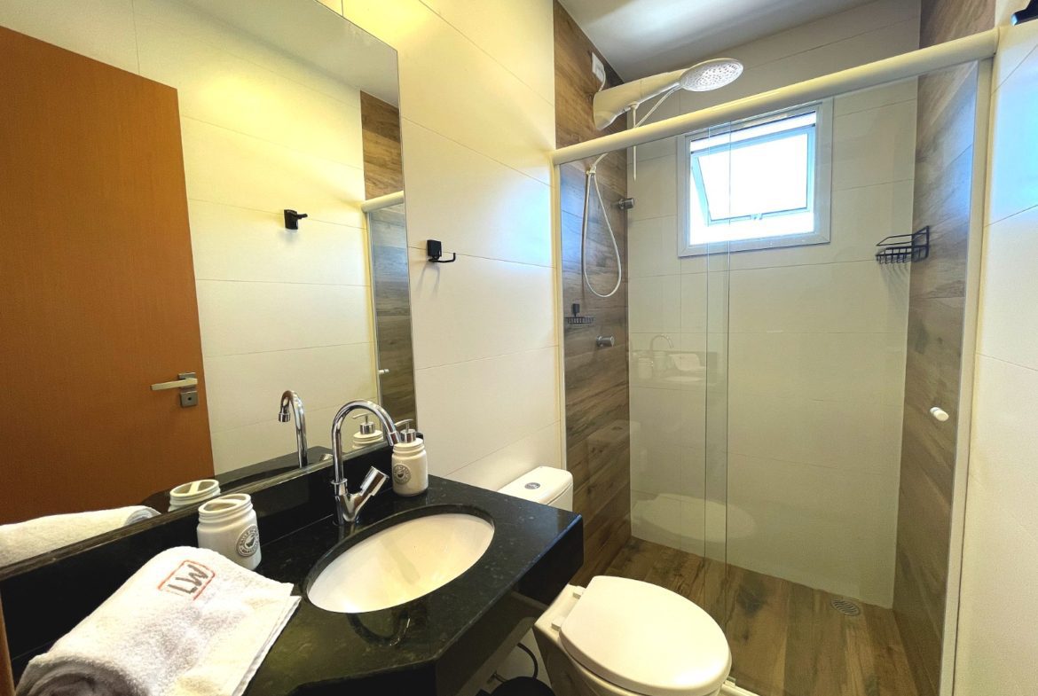 Banheiro do apartamento com bancada e box de vidro