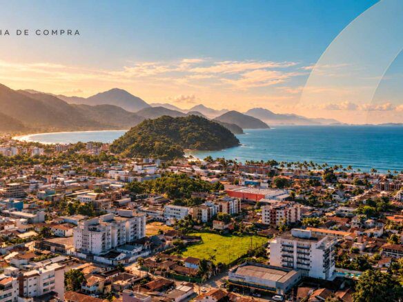 Vista aérea de obra em andamento em Ubatuba com área urbana, mar e morros ao fundo