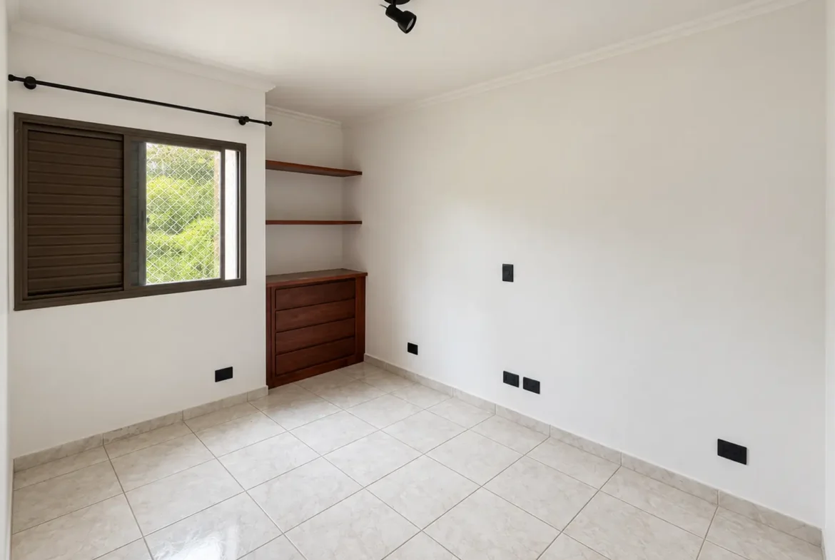 Dormitório do apartamento com janela e armário