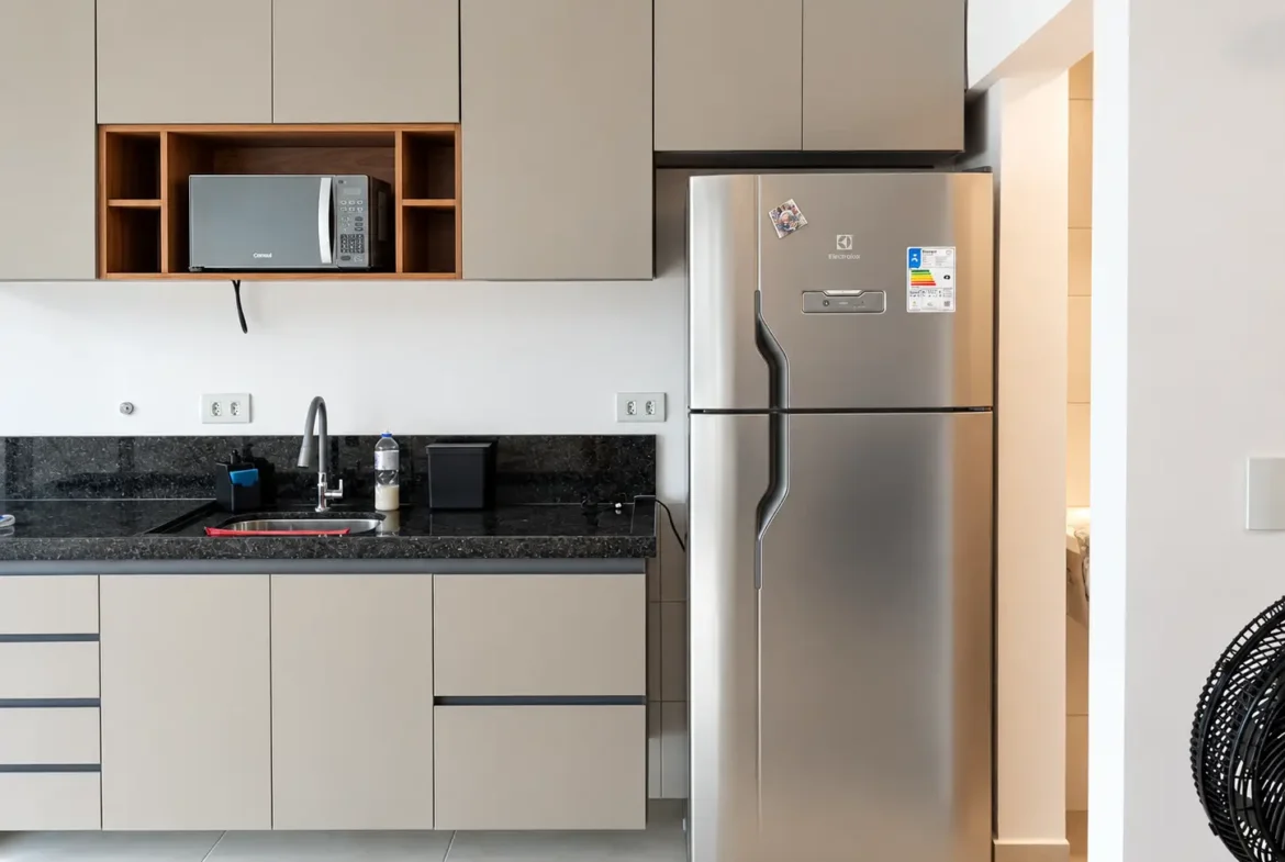Cozinha com armários planejados, bancada escura e geladeira de inox.