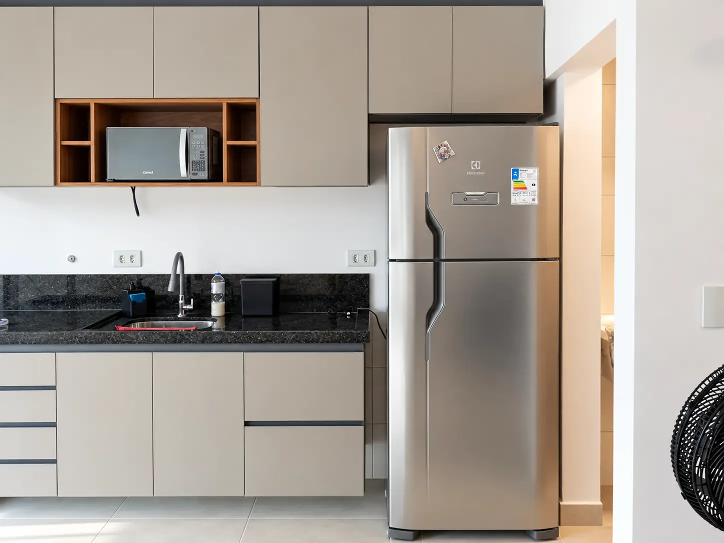 apartamento-itagua-66m2-lg116-moveis-cozinha Cozinha com armários planejados, bancada escura e geladeira de inox.