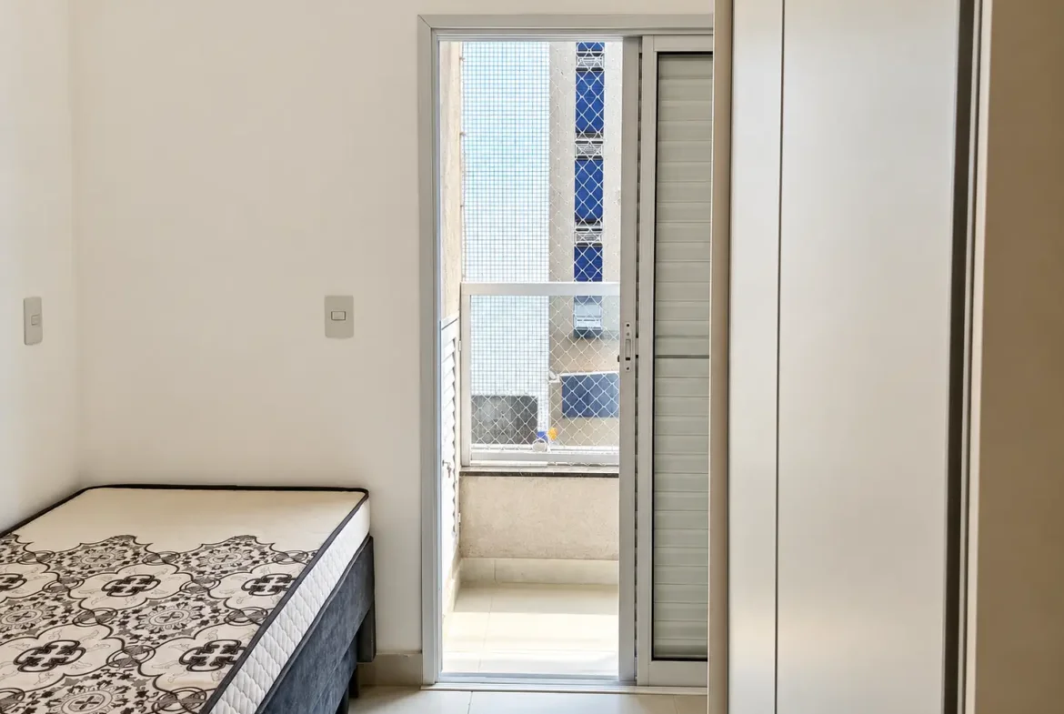 suite do apartamento no Itaguá com cama de casal cinza e paredes claras.