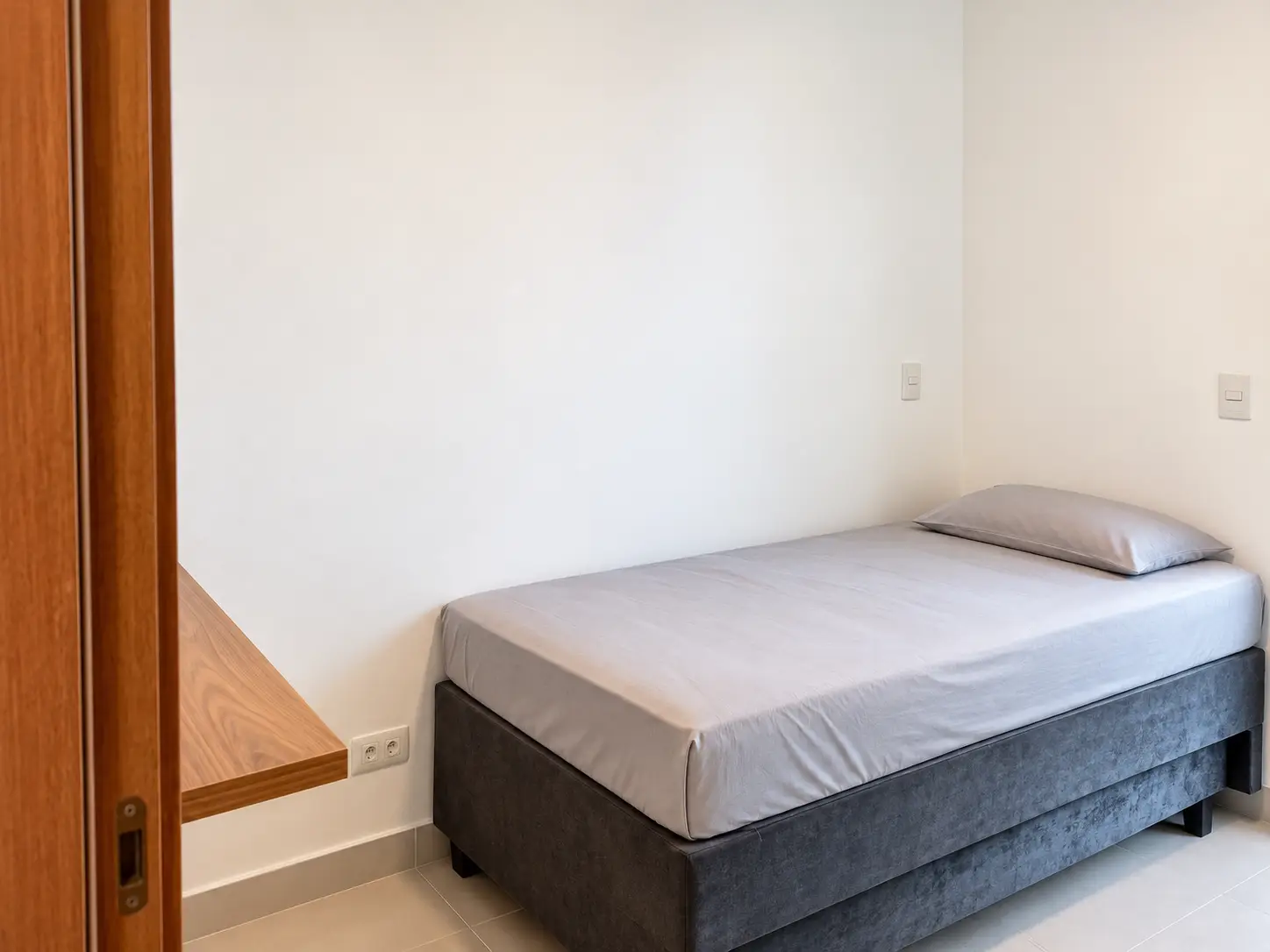 apartamento-itagua-66m2-lg116-quarto Dormitório do apartamento no Itaguá com cama de casal cinza e paredes claras.