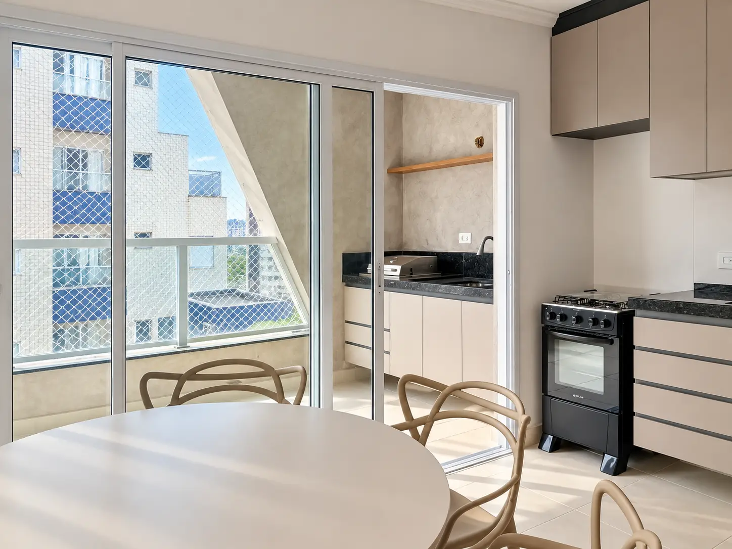 apartamento-itagua-66m2-lg116-sacada-vista Sacada com bancada e armários, separada da cozinha por portas de vidro.