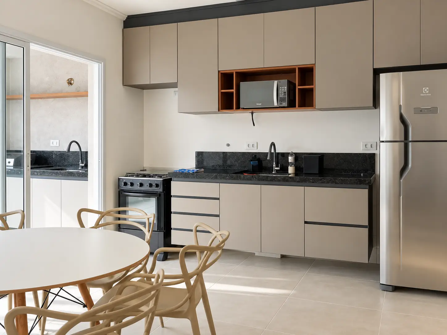 apartamento-itagua-66m2-lg116-sala-cozinha Cozinha com armários planejados e acesso à sacada por porta de vidro.
