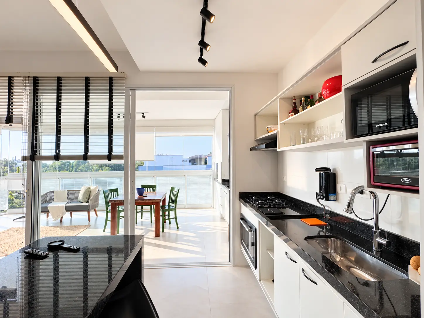 apartamento-itagua-lg117-113-82m2-cozinha-integrada-03 Cozinha integrada à área social, com bancada escura, armários planejados e iluminação natural.