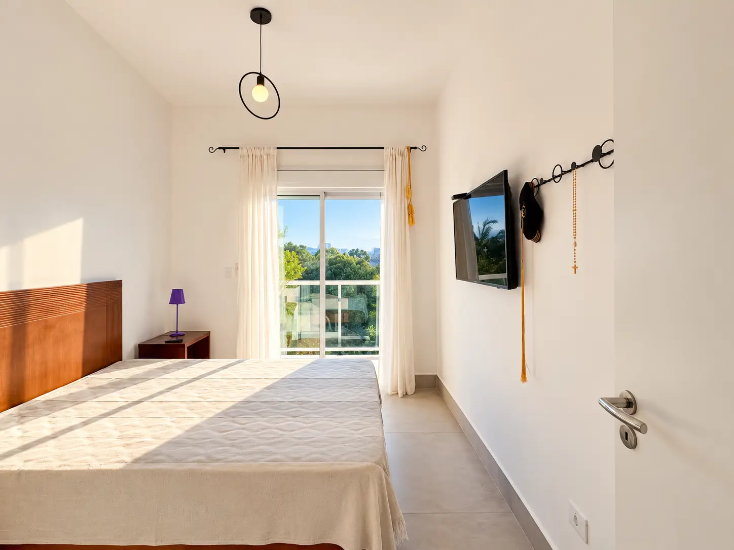 apartamento-itagua-lg117-113-82m2-dormitorio Dormitório com cama, móveis claros, televisão na parede e janela.