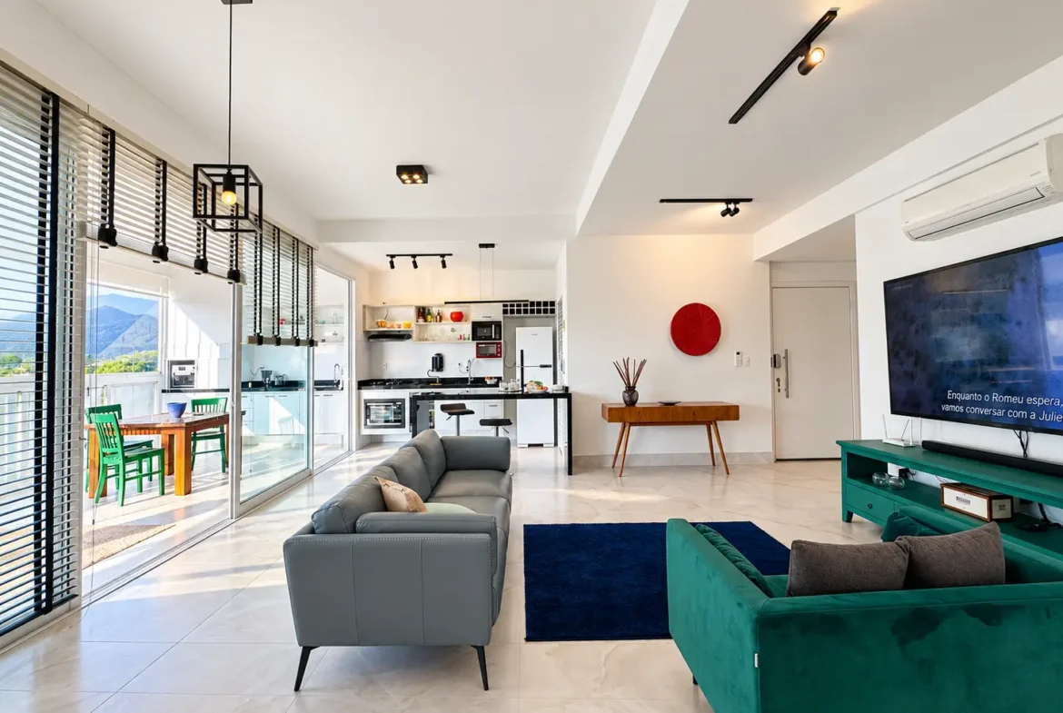 Sala de estar integrada com sofás, televisão, móveis planejados e janelas amplas.