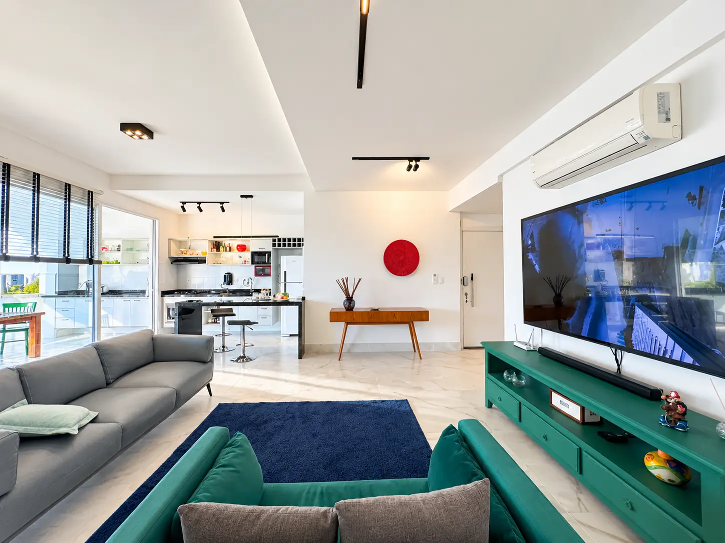 apartamento-itagua-lg117-113-82m2-sala-integrada-02 Sala de estar com sofás, televisão, parede decorativa e iluminação natural.