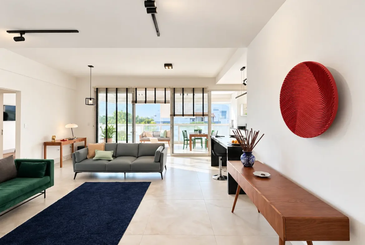 Vista da sala integrada com sofá, painel decorativo e acesso à varanda.