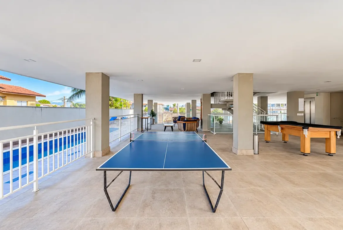 Área de lazer com mesa de tênis de mesa e espaço de convivência coberto.