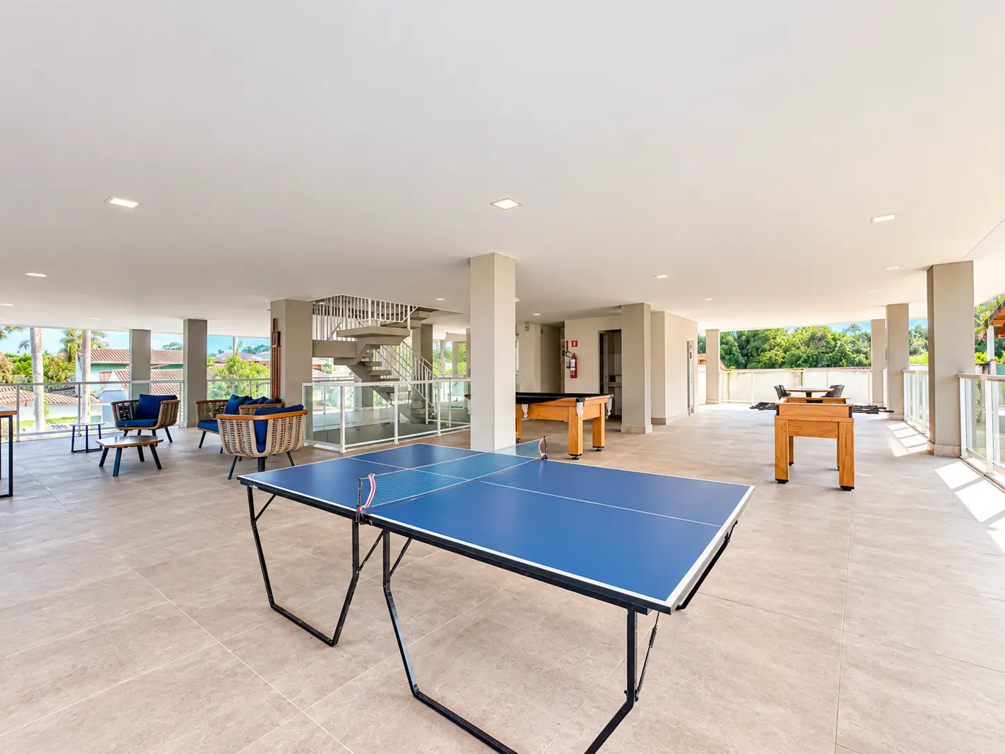 apartamento-itagua-lg117-113-82m2-sala-jogos-e-festa Salão de convivência com mesa de tênis de mesa, mesas e cadeiras.