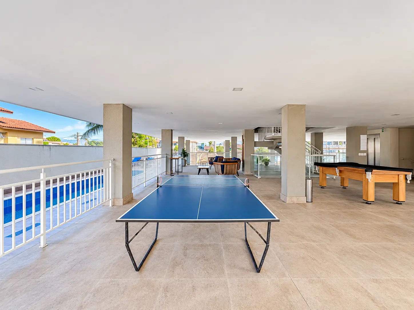 apartamento-itagua-lg117-113-82m2-sala-jogos Área de lazer com mesa de tênis de mesa e espaço de convivência coberto.