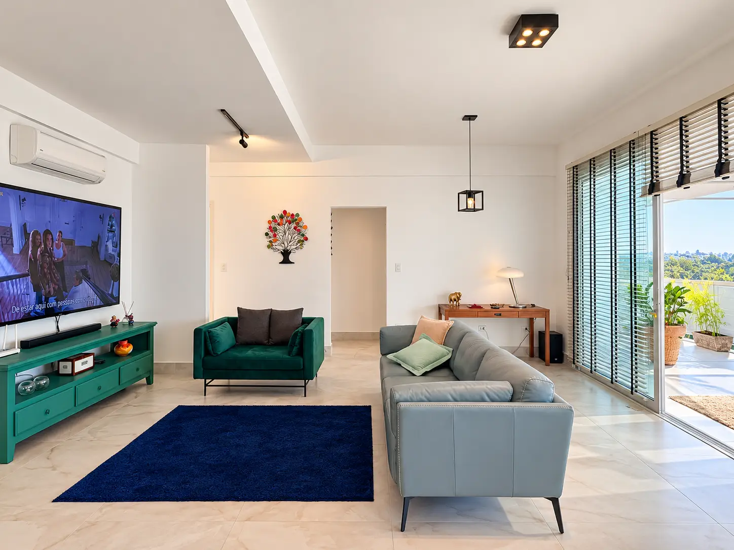apartamento-itagua-lg117-113-82m2-sala-tv Sala de televisão com sofá, poltronas e porta de vidro de acesso à varanda.
