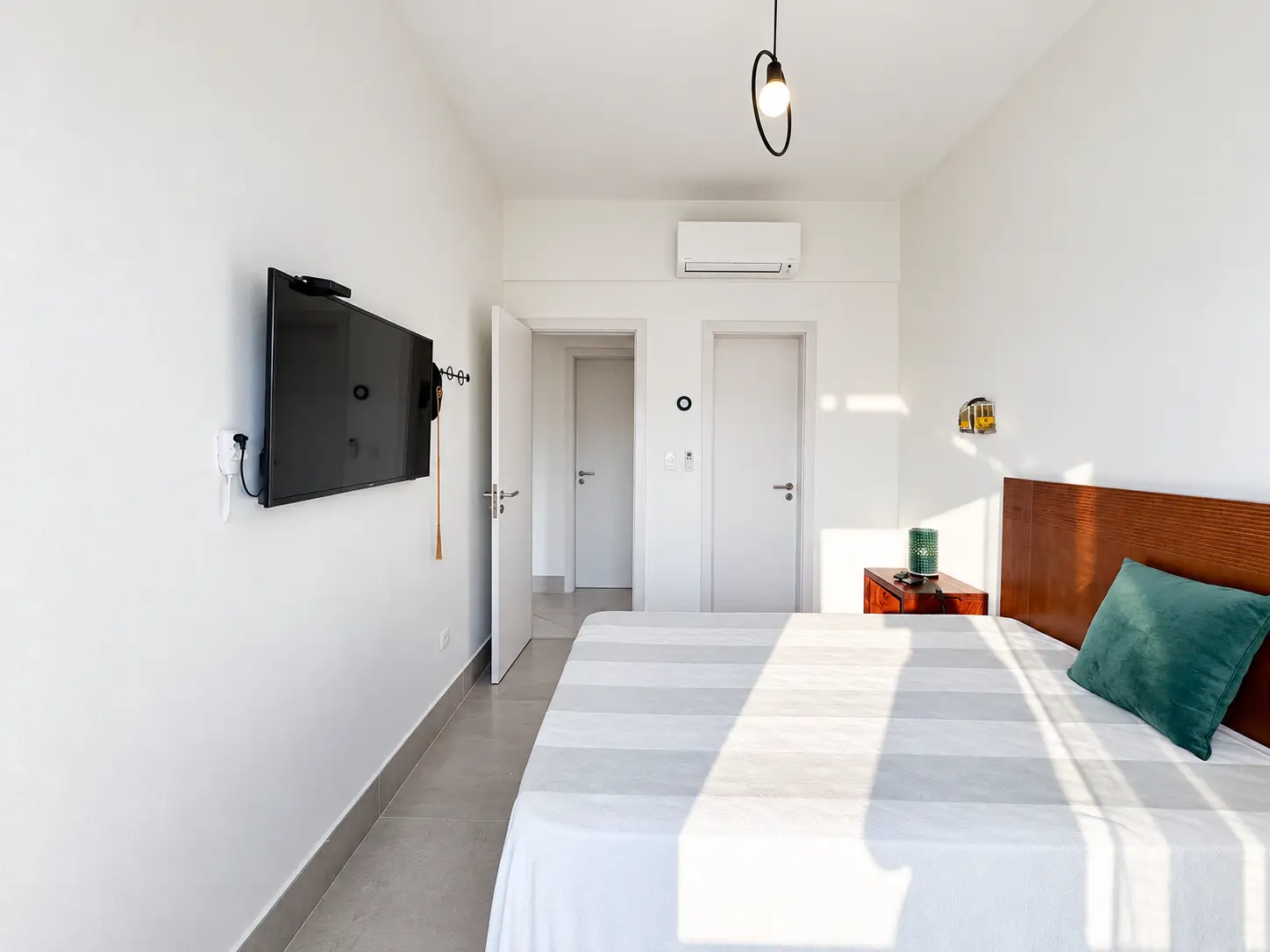 apartamento-itagua-lg117-113-82m2-suite-02 Outro ângulo da suíte, com cama de casal, televisão na parede e móveis claros.