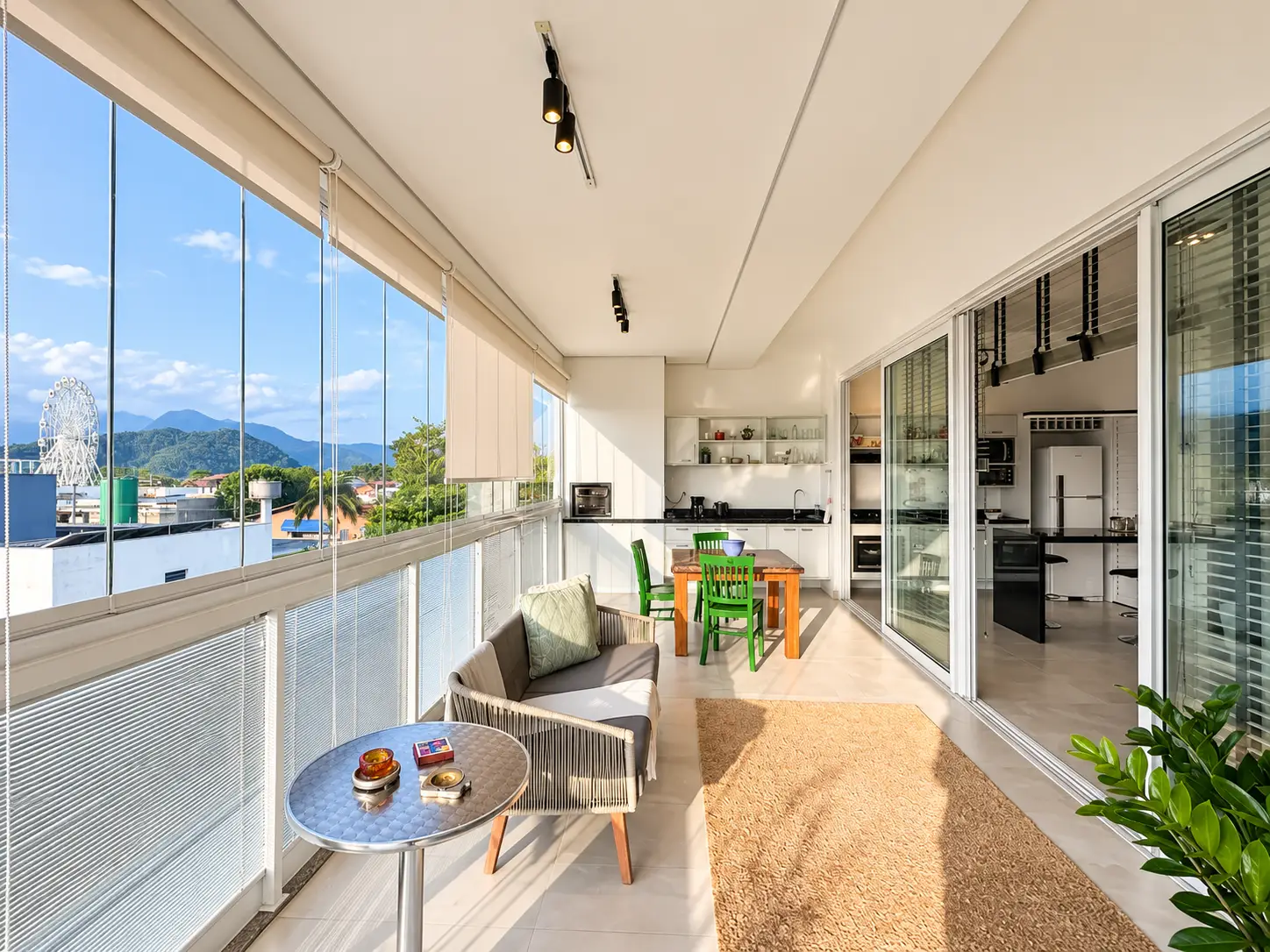 apartamento-itagua-lg117-113-82m2-varanda-gourmet Varanda gourmet espaçosa com mesa de jantar, cadeiras e fechamento em vidro.