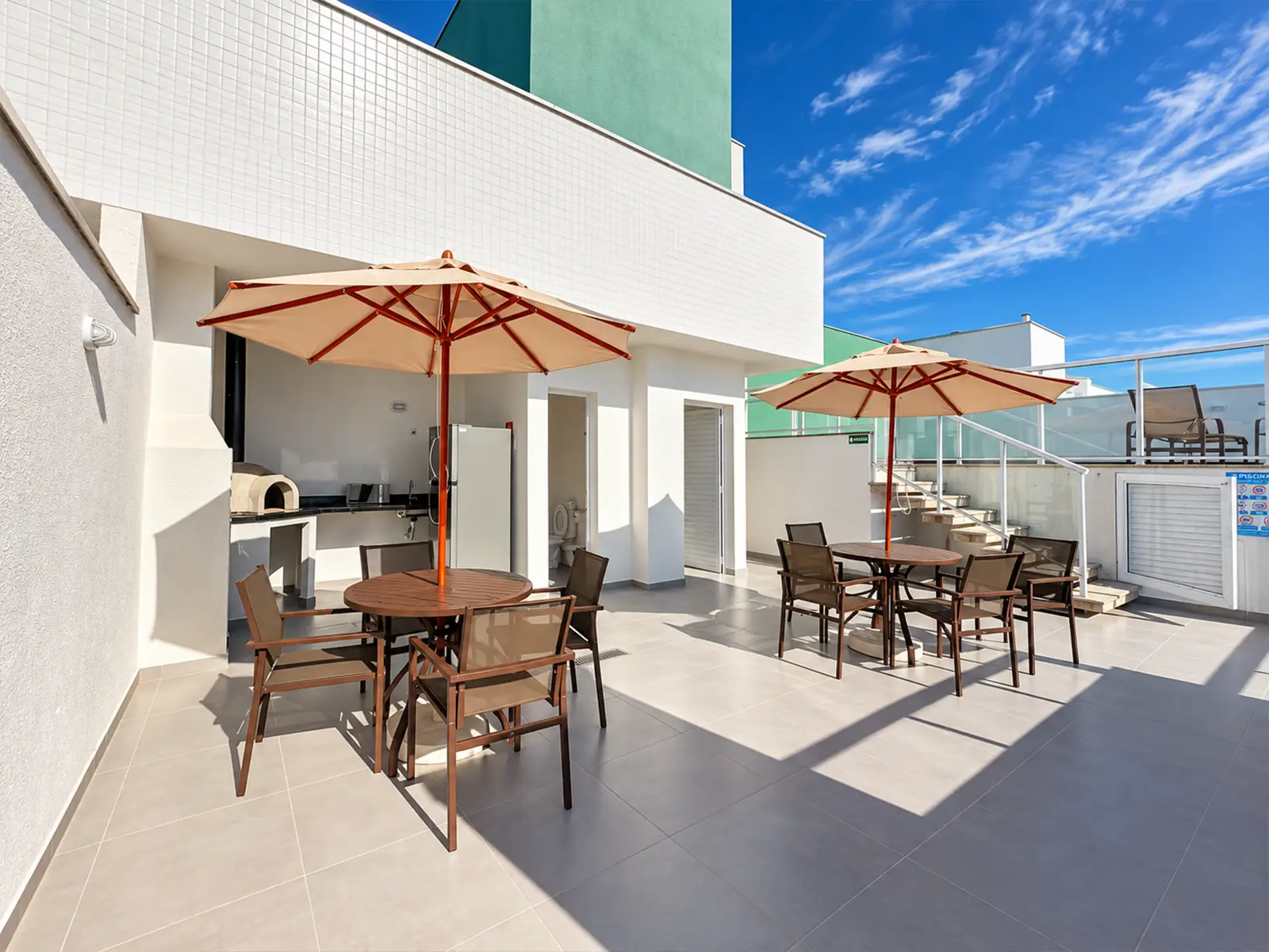 apartamento-itagua-ubatuba-90m2-rooftop-2 Espaço externo do condomínio com mesas e área de convivência