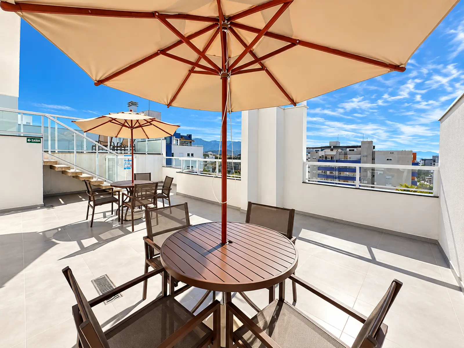 apartamento-itagua-ubatuba-90m2-rooftop Área externa do condomínio com mesas e guarda-sol