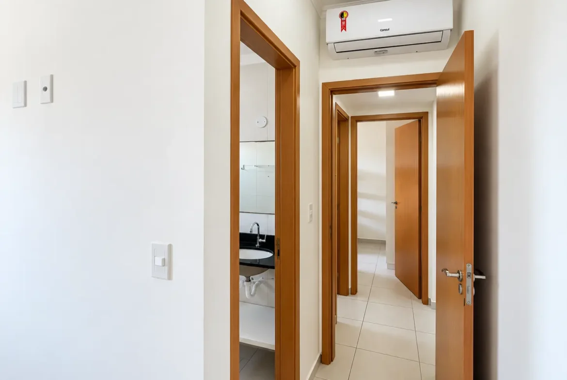 Corredor interno do apartamento com portas de madeira e paredes claras.