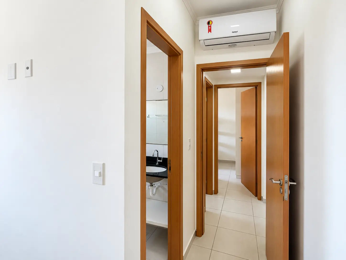 apartamento-praia-grande-corredor-interno Corredor interno do apartamento com portas de madeira e paredes claras.