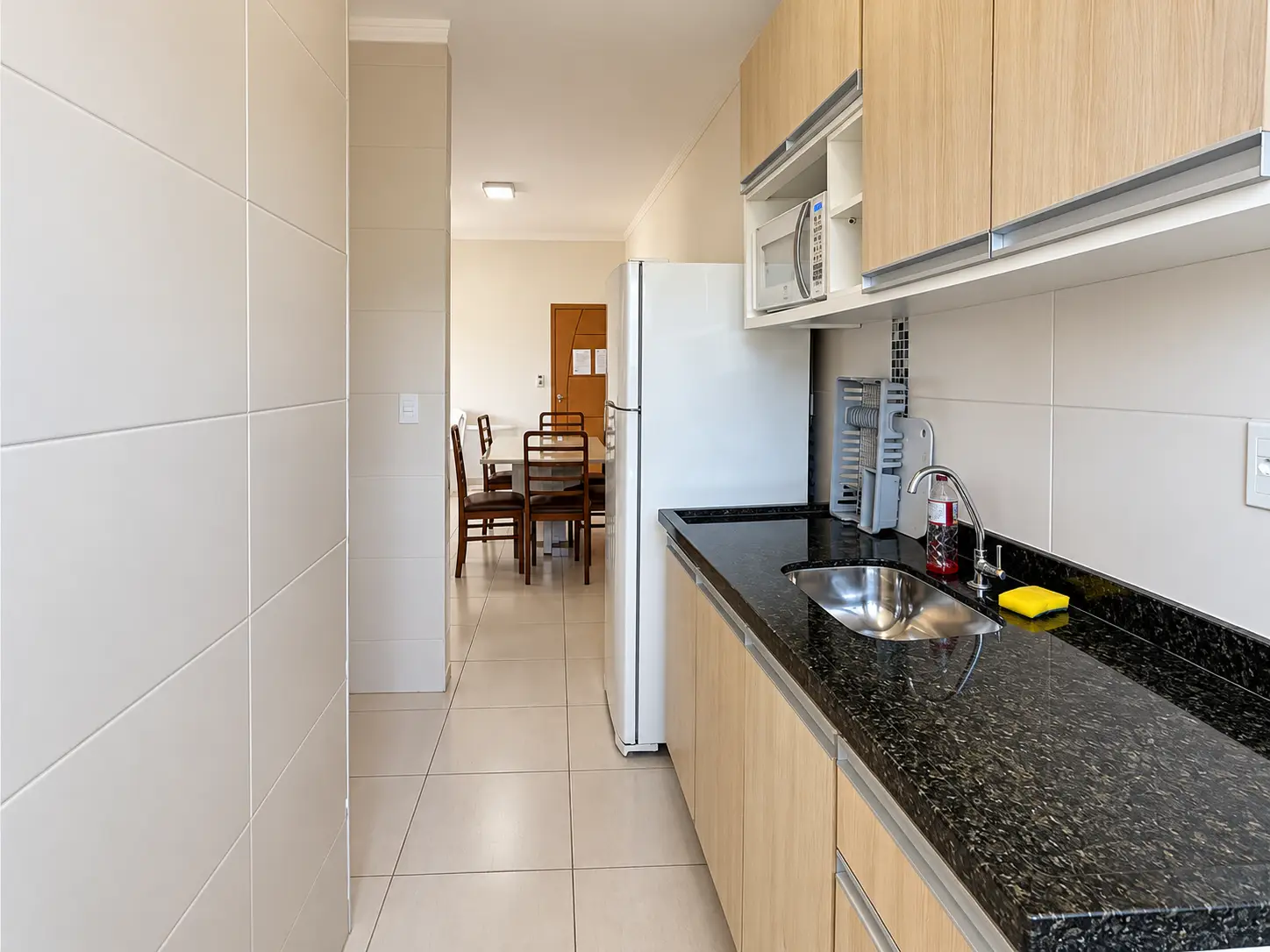 apartamento-praia-grande-cozinha Cozinha com armários, pia e bancada escura.