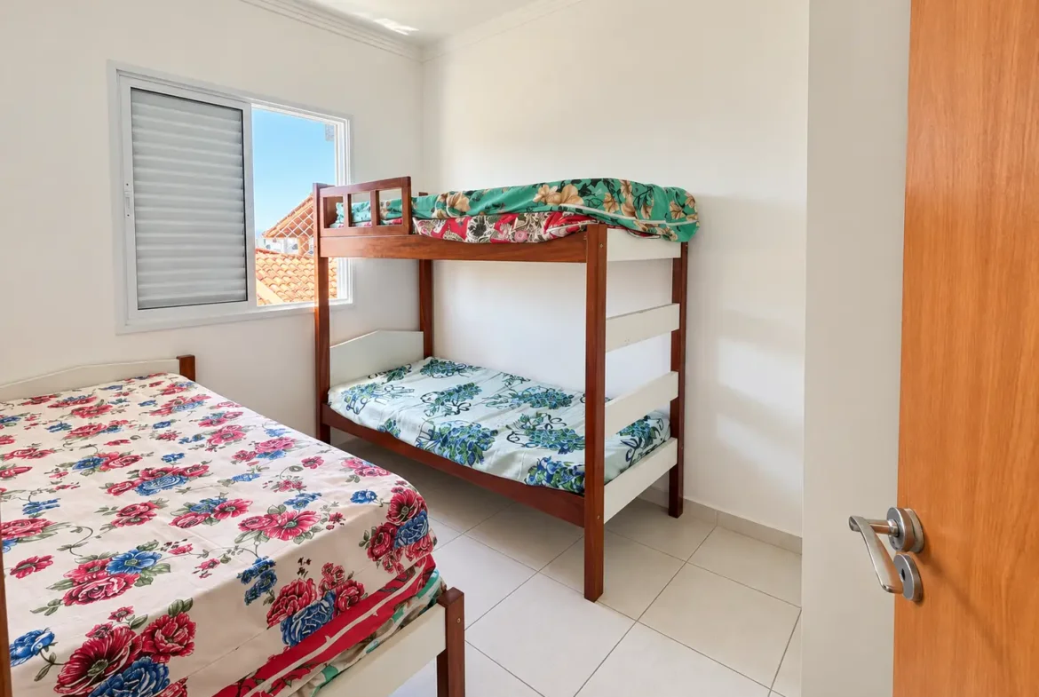 Segundo dormitório com beliche e roupa de cama estampada.