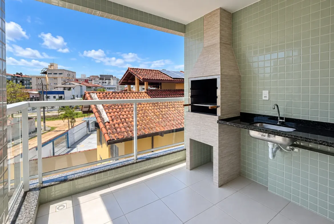 Varanda gourmet com churrasqueira, bancada e vista para as edificações da região.
