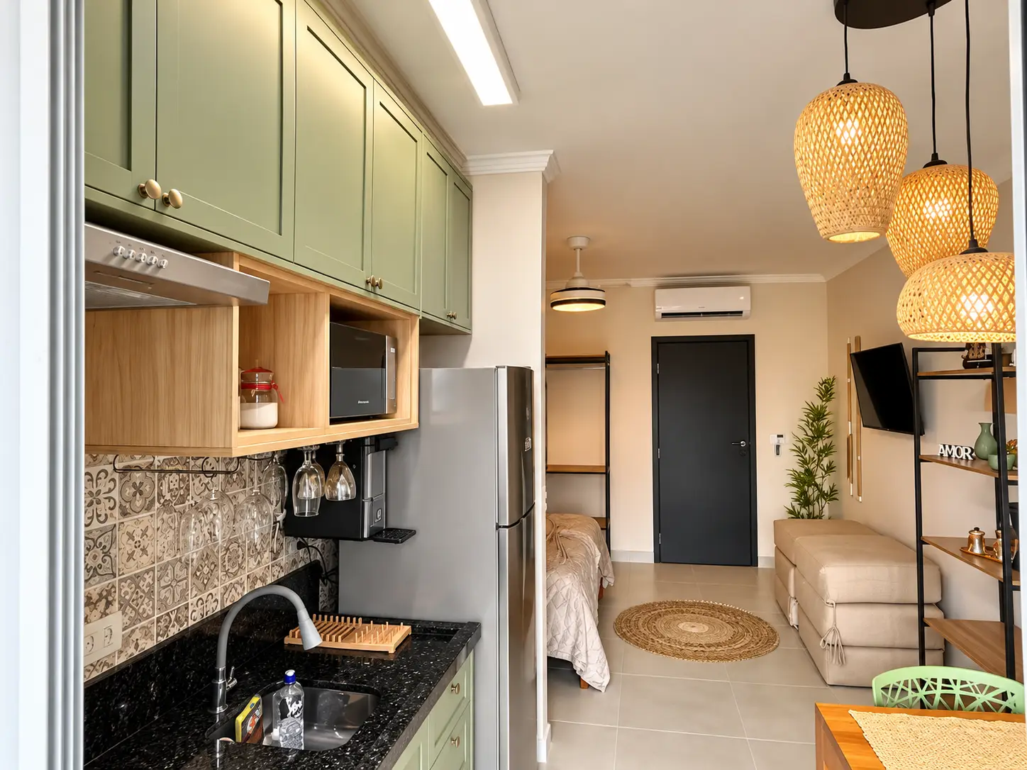loft-35-m2-Itaguá-cozinha-quarto Vista da cozinha do loft integrada aos demais ambientes, com armários e iluminação pendente.