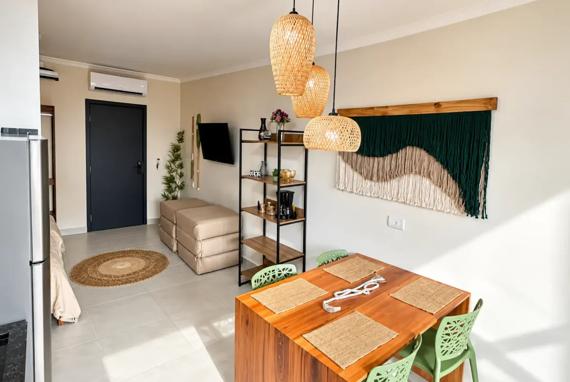 Sala do loft com sofá, televisão na parede e estante com objetos decorativos.