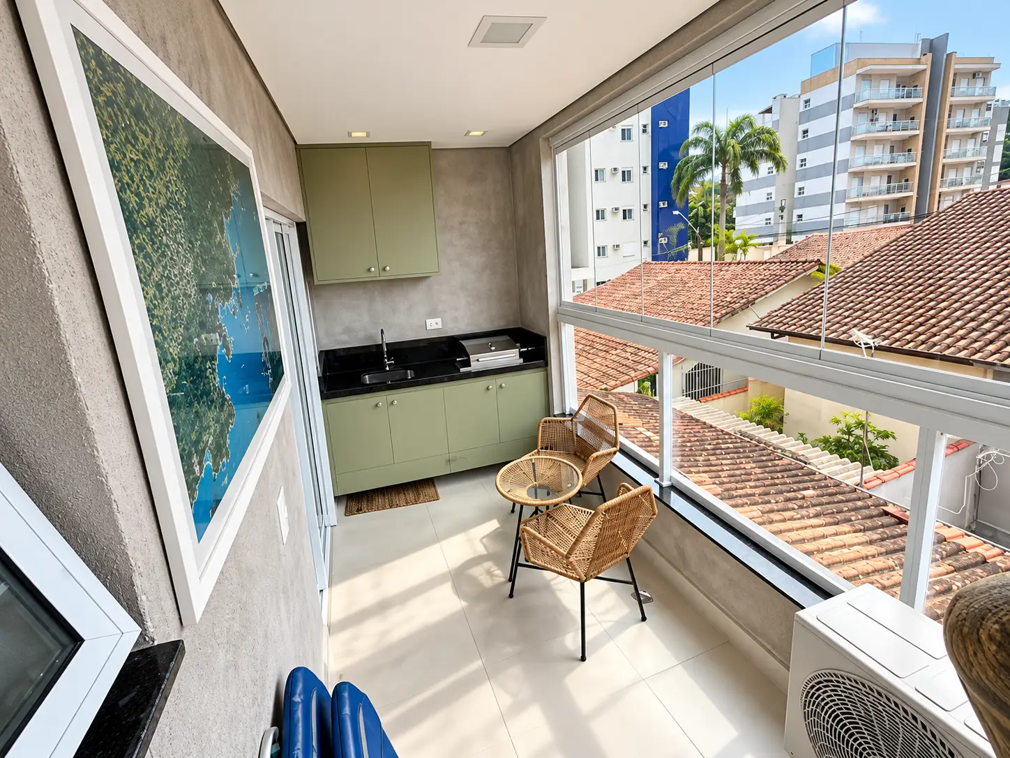 loft-35-m2-Itaguá-varanda-gourmet-02 Varanda do loft com mesa, cadeiras e vista para a região urbana.