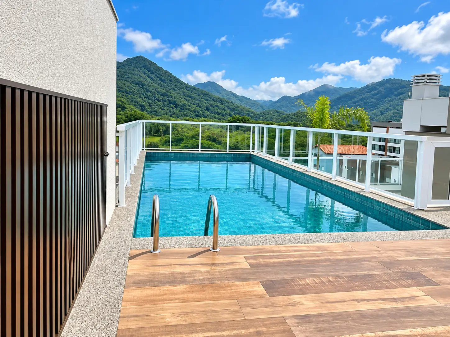 loft-35-m2-Itaguá-varanda-piscina-02 Outro ângulo da piscina no rooftop, com guarda-corpo de vidro e vista para as montanhas.