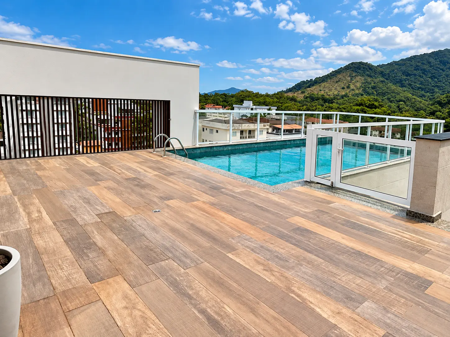 loft-35-m2-Itaguá-varanda-piscina-03 Área de lazer no rooftop com deck de madeira, piscina e vista para as montanhas.