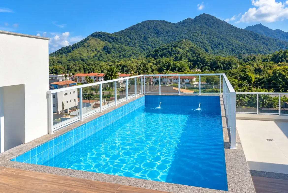 Piscina na cobertura do edifício, com deck e montanhas ao fundo.
