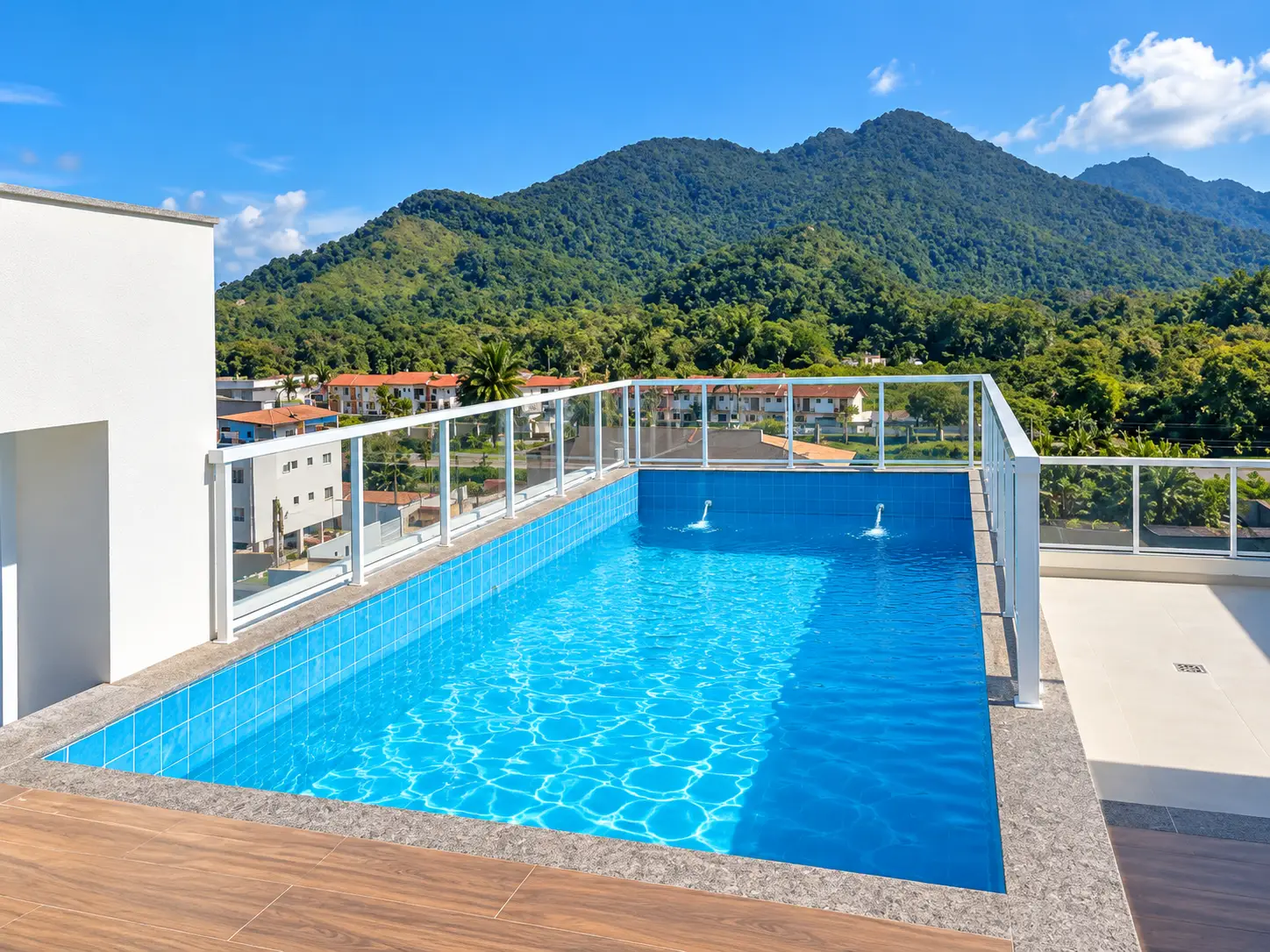 loft-35-m2-Itaguá-varanda-piscina Piscina na cobertura do edifício, com deck e montanhas ao fundo.