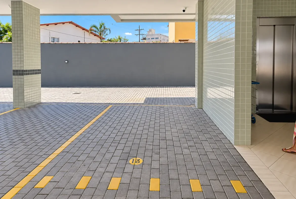 Garagem coberta do condomínio com vagas demarcadas no piso.