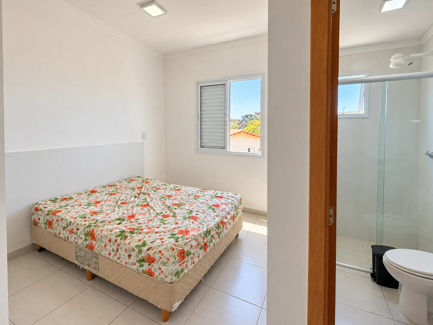 praia-grande-suite-acesso-banheiro Suíte com cama de casal e porta de acesso ao banheiro.